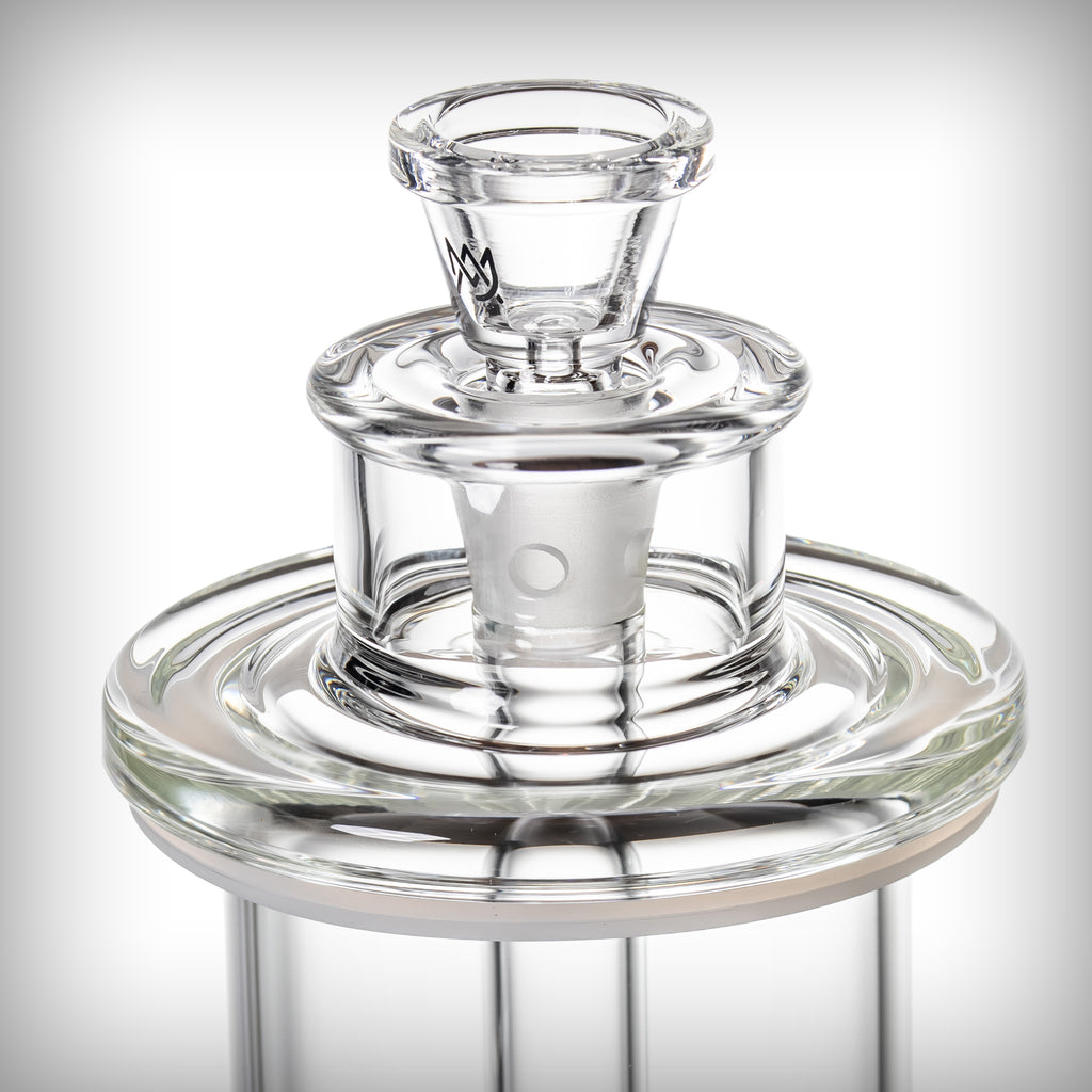 Angled close-up of the MJ Arsenal Piston Gravity Bong glass slide and surrounding circular glass assembly.