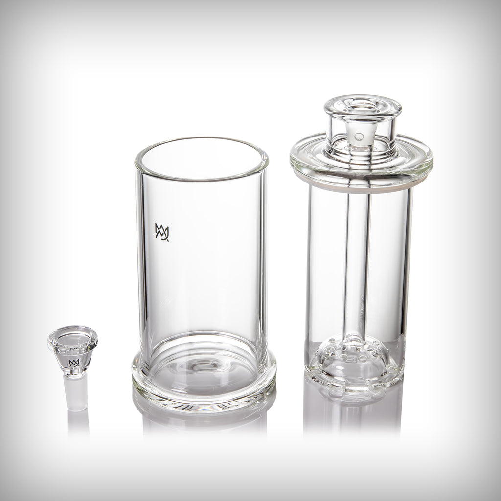 Disassembled MJ Arsenal Piston Gravity Bong showing the outer glass shell, internal core, and removable glass slide.